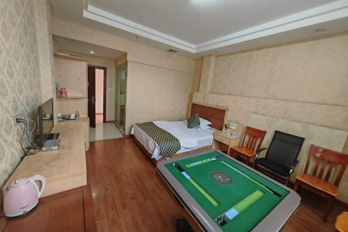 Habitación de hotel con cama, mesa de billar, escritorio con hervidor y televisión.
