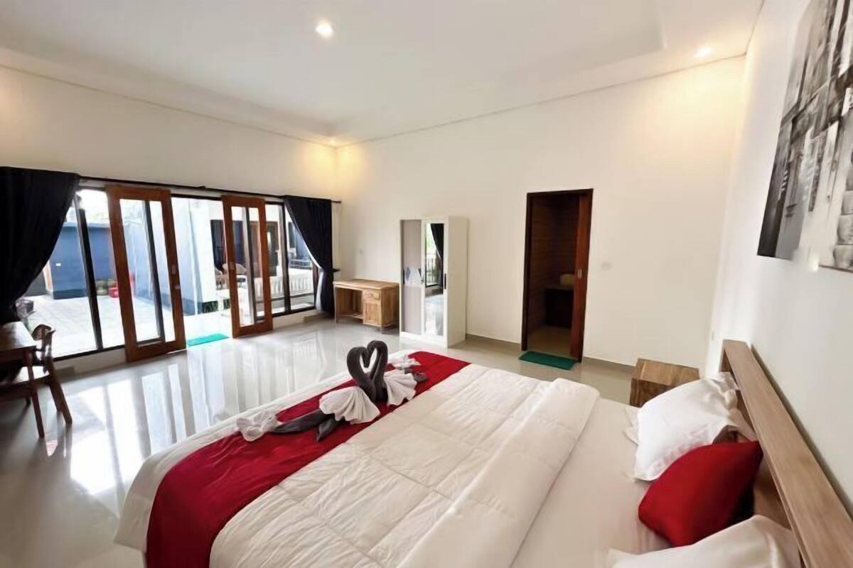Une chambre d’hôtel avec un grand lit, un bureau et une vue sur l’extérieur, visible à travers les portes vitrées.