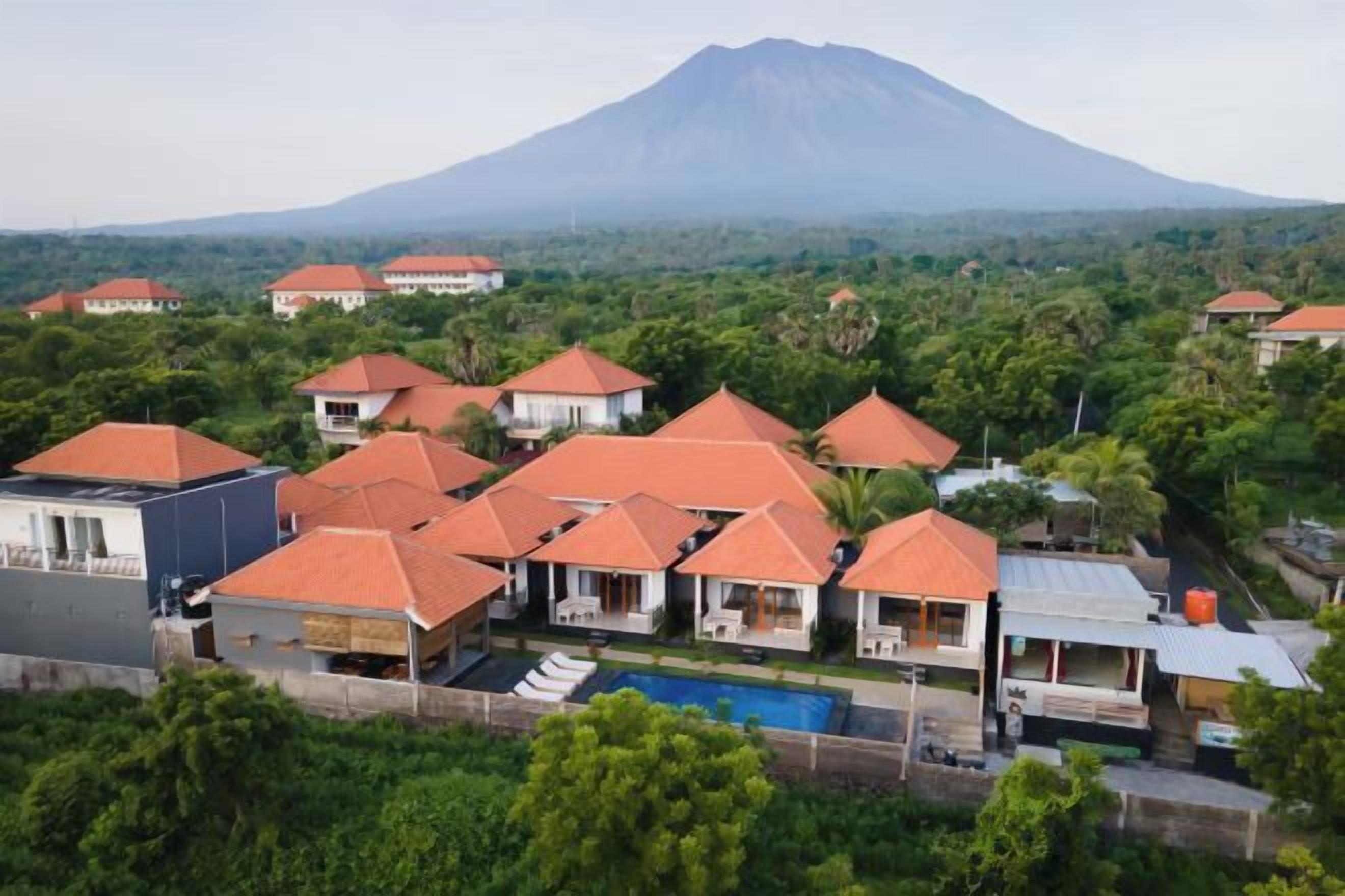 A resort with multiple buildings, a swimming pool, and a mountain in the background.