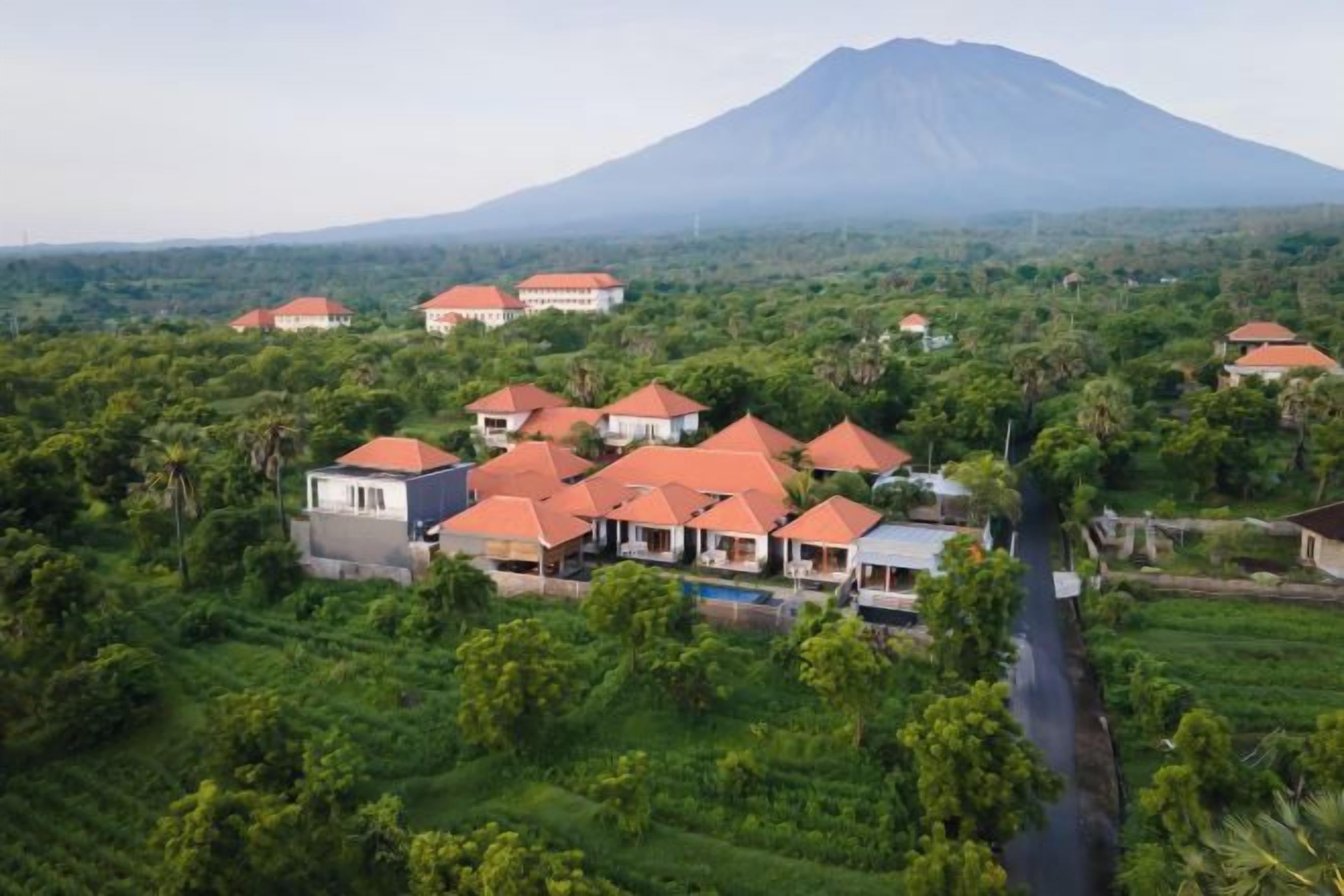 A resort with multiple buildings, a river, and a mountain in the background.