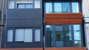 Un bâtiment moderne dont la façade combine des éléments en bois et en métal, avec de grandes fenêtres et des câbles électriques apparents.