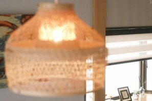 Una lampada a sospensione con decorazioni intrecciate, una finestra con vista e un quadro incorniciato su un tavolo.