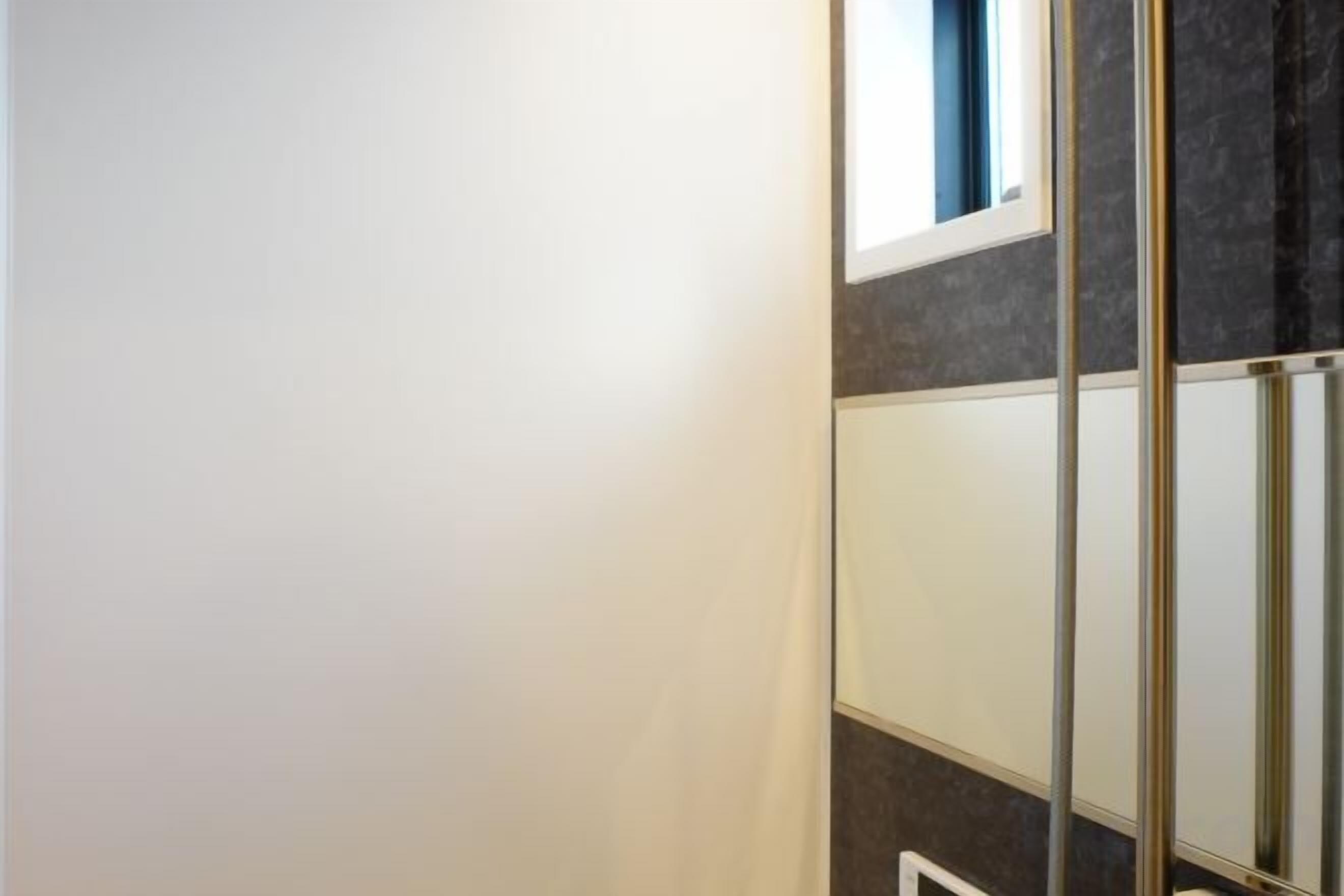 Een hoek van een kamer met een witte muur, een raam en een gedeeltelijk zicht op een donkere muur.