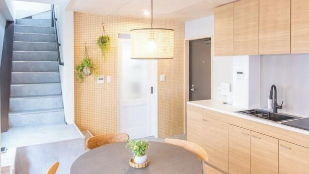 Une cuisine moderne avec des meubles en bois, une table de salle à manger ronde et un escalier.