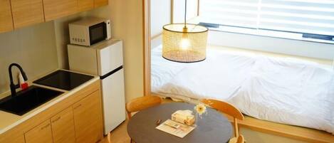 A compact kitchen with a microwave, a sink, and a dining area with a table and chairs.