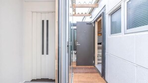 Un couloir étroit avec un plancher en bois, une porte en verre et une porte sombre au fond.