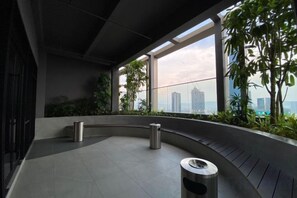 Ein modernes Interieur mit einem gebogenen Balkon, Metallmülltonnen und Blick auf die Stadtlandschaft.