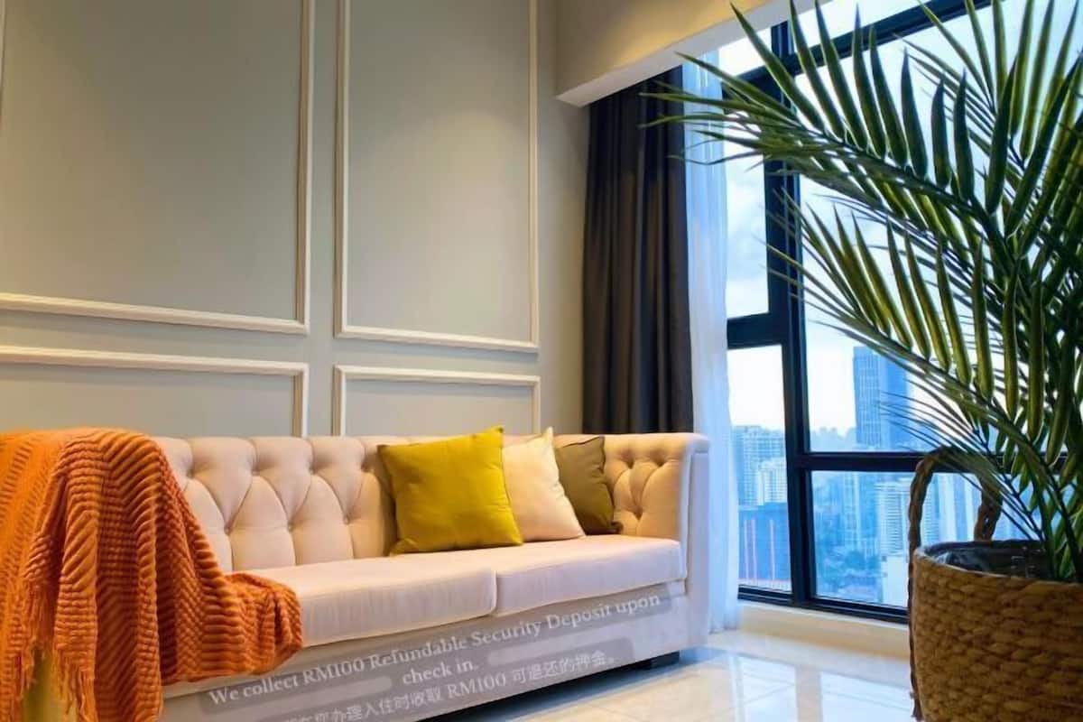 Una habitación de hotel moderna con un ventanal grande, un sofá cómodo y una planta en maceta.