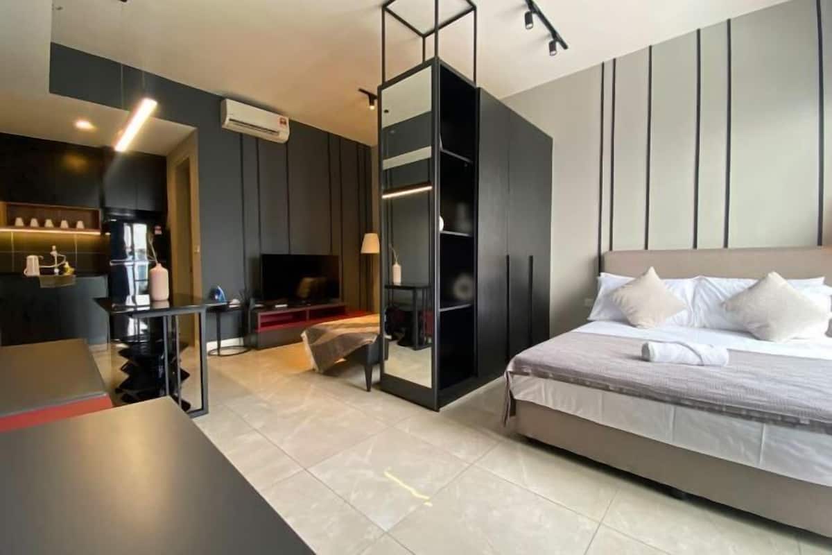Una habitación de hotel moderna con cama, escritorio, televisión y armario.