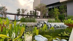 A rooftop garden with a pond, rocks, and various plants. - Axon Bukit Bintang by Janice's Homestay (Kuala Lumpur)