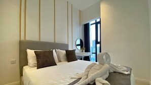 A modern hotel room with a large bed, a round mirror, and a view of the city through large windows. - Axon Bukit Bintang by Janice's Homestay (Kuala Lumpur)
