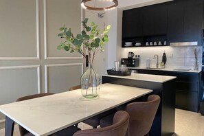 Een moderne keuken met donkere kastjes, een witte aanrecht en een vaas met groene bladeren.