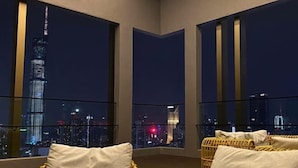 A balcony with wicker furniture and a cityscape view at night. - Axon Bukit Bintang by Janice's Homestay (Kuala Lumpur)