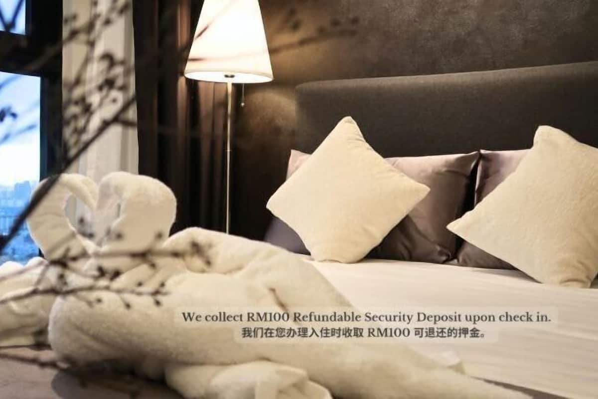 Una habitación de hotel con cama, almohadas, lámpara y ventana con vistas.