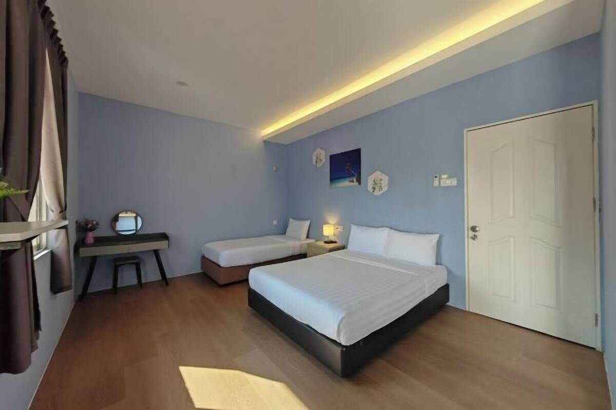 Una camera d'albergo con un letto grande, due letti più piccoli, una scrivania e una sedia.