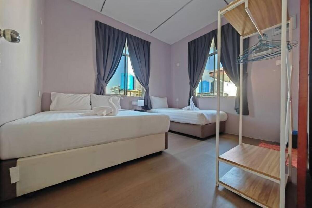 Camera d'albergo con due letti, pavimento in legno e porta-oggetti in metallo.