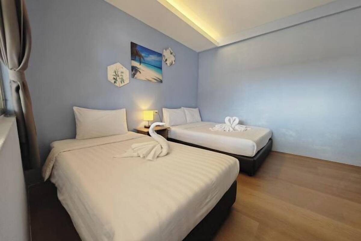 Una camera d'albergo con due letti, un comodino, una lampada e opere d'arte alle pareti.