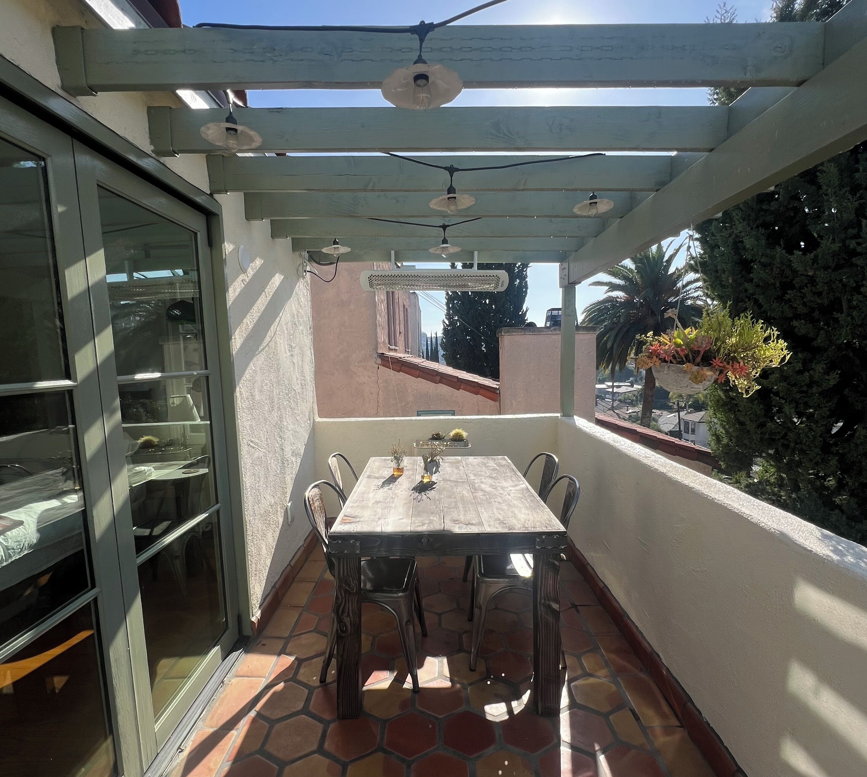 A covered patio with a table and chairs, a pergola overhead, and a view of the surrounding area.