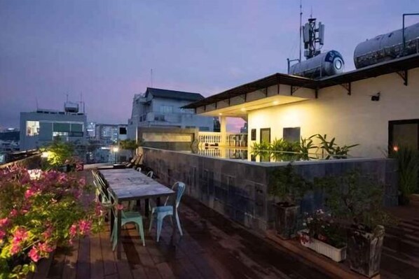 A rooftop terrace with a dining table and chairs, surrounded by potted plants and a stone wall. - Yen Living Binh Th Nh (Ho Chi Minh Municipality)