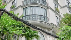 Un edificio de varios pisos con un balcón curvo, ventanas amplias y vegetación circundante.