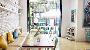 Un rincón acogedor con pared de ladrillo blanco, una mesa de madera y vistas al patio exterior.
