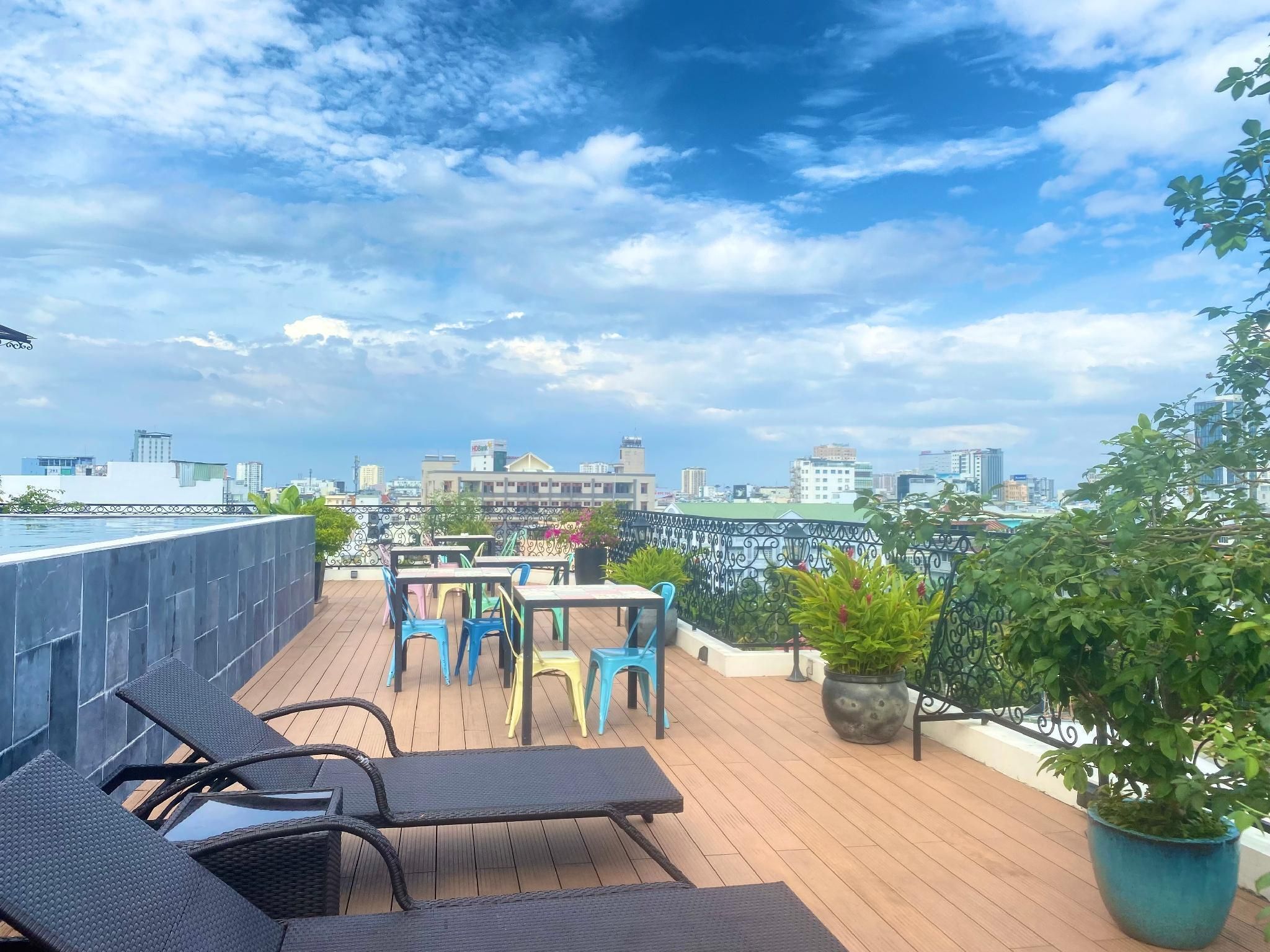 A rooftop terrace with outdoor seating, a view of the city skyline, and potted plants.