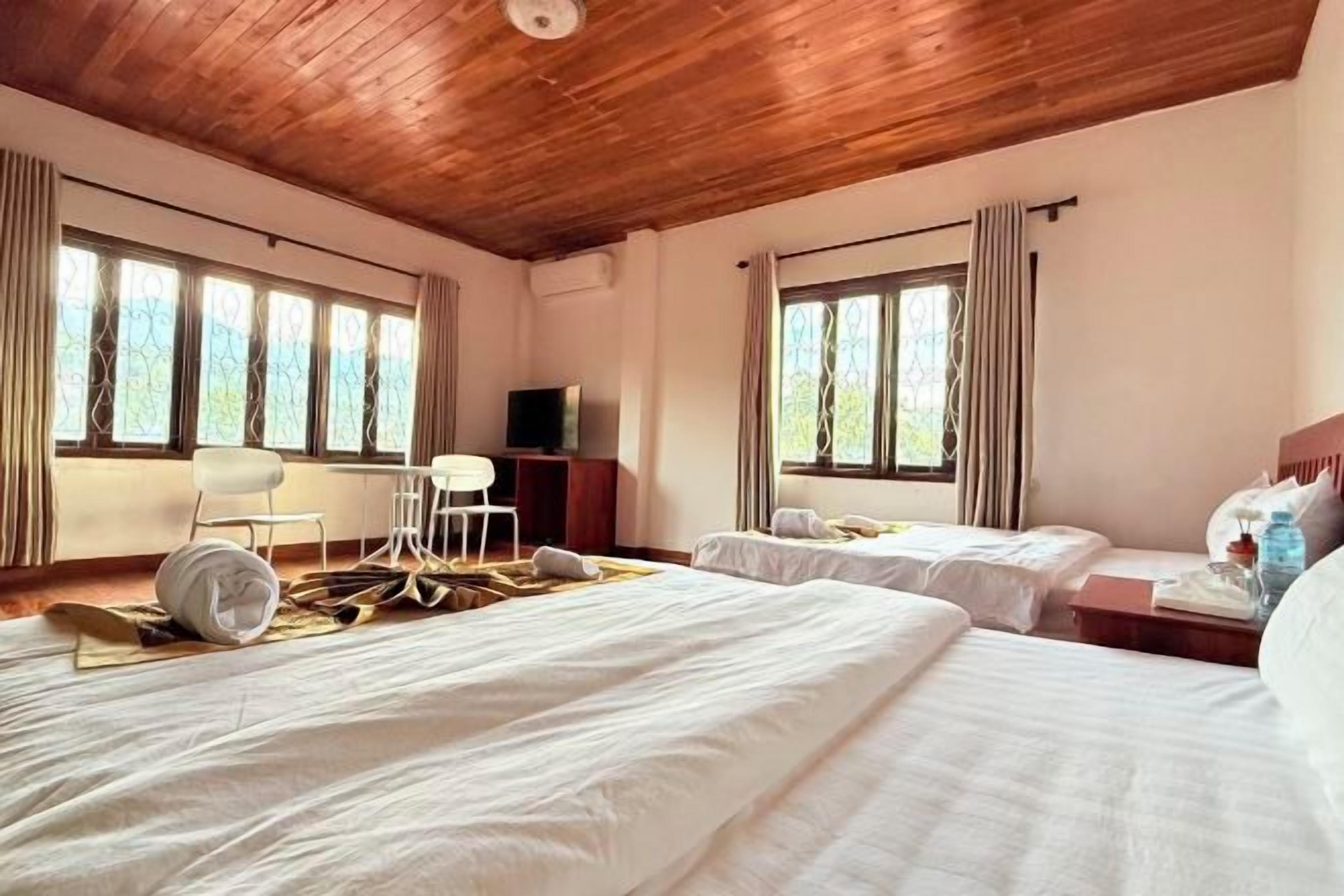 Habitación de hotel con dos camas, televisor, escritorio y una silla.