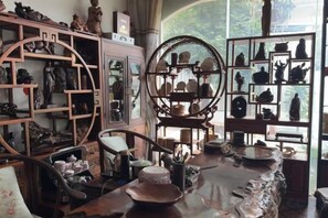A room with traditional Chinese furniture, including a circular wooden cabinet and shelves with pottery. - YouBang International Hotel (Luang Prabang)