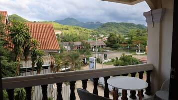 A balcony with a view of a town, a table, and a chair.