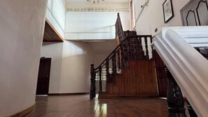 Une pièce spacieuse avec un escalier en bois, un lustre et un lit.