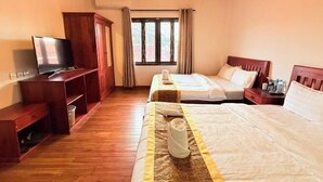 Une chambre d’hôtel avec deux lits, une télévision, des meubles en bois et une fenêtre avec des rideaux.