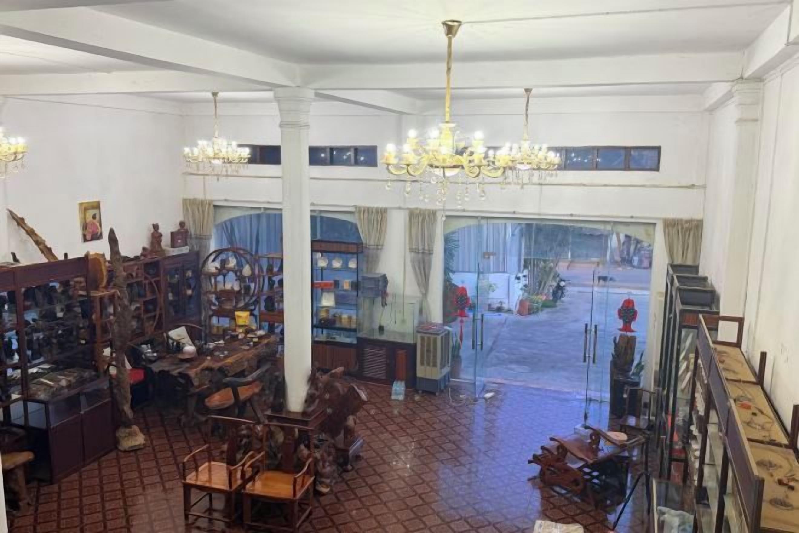 A spacious room with a high ceiling, chandeliers, and a large window.