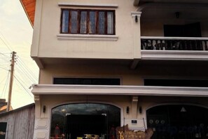 A two-story building with a balcony on the upper floor and a large arched entrance on the ground floor. - YouBang International Hotel (Luang Prabang)