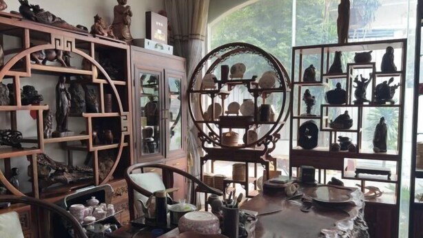 Une pièce où se trouve une table en bois sur laquelle sont exposées diverses pièces de poterie et sculptures.