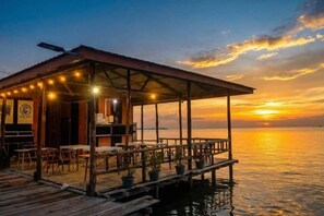 A wooden dock with a covered seating area, tables, and potted plants. - Turtle Garden Resort @ Semporna (Semporna)