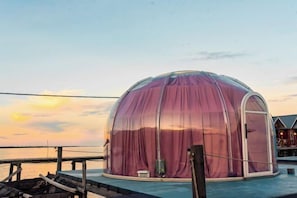 A dome-shaped tent-like structure with a door, situated on a dock with a view of the water and a building in the background. - Turtle Garden Resort @ Semporna (Semporna)