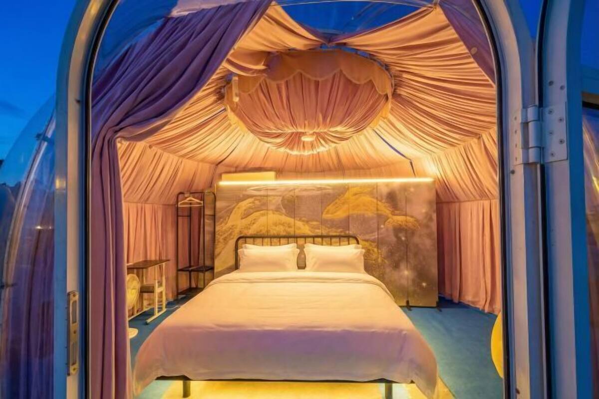 Ein Zimmer mit einem Bett, Vorhängen, einer Kristallleuchtre und einer Wand mit Bergmotiv.
