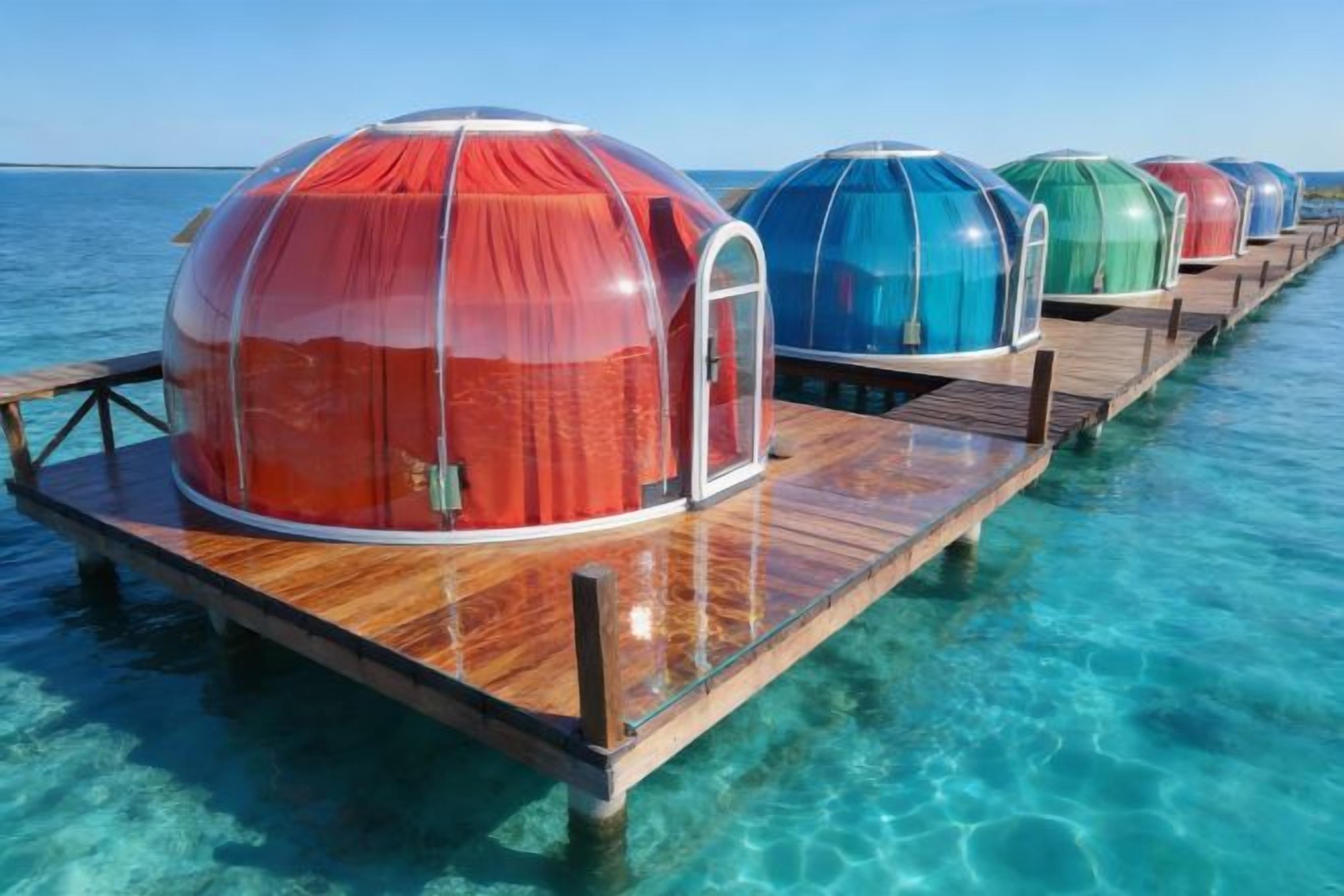 Bungalow sull'acqua con struttura a cupola, terrazza in legno e acque cristalline.