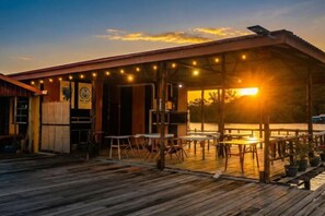 A wooden deck with tables and chairs, a covered area with string lights, and a building entrance. - Turtle Garden Resort @ Semporna (Semporna)
