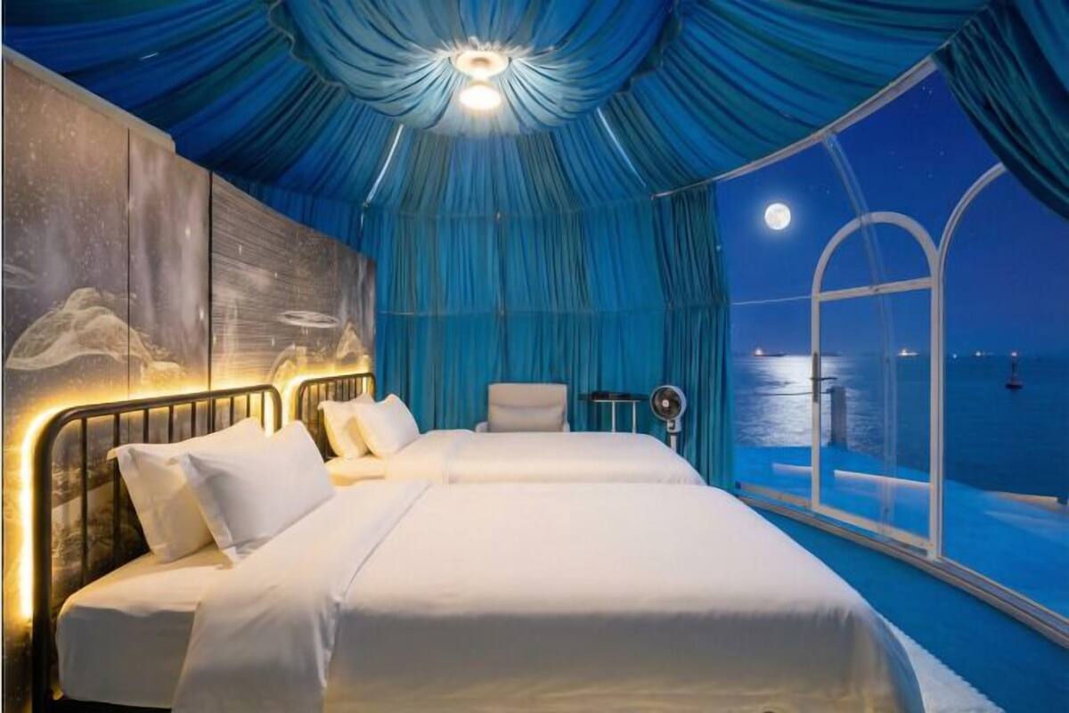 Ein Schlafzimmer mit zwei Betten, einem großen Fenster und Meerblick.