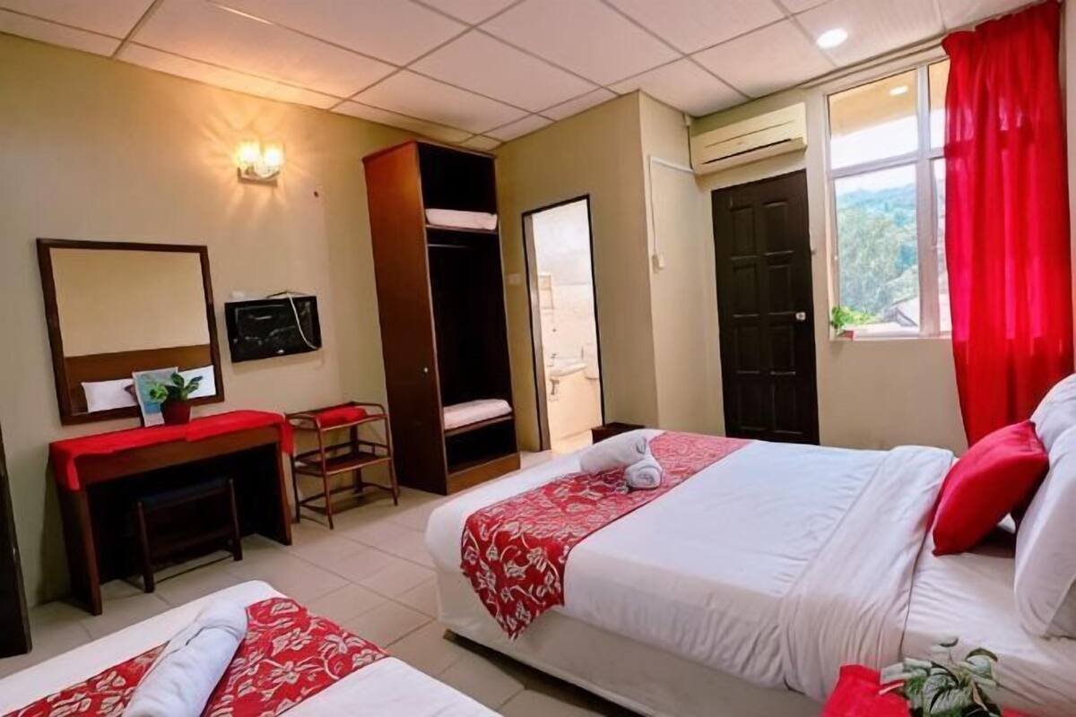 Une chambre d’hôtel avec deux lits, un bureau, un miroir, une télévision et une armoire.