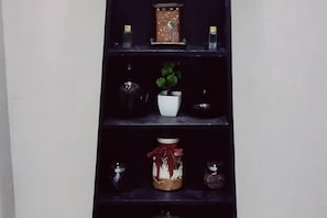Una estantería con adornos como una planta, velas y frascos.