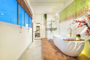 A modern bathroom with a large bathtub, a glass shower enclosure, and a view of the sky through large windows. - Shin Hotel Chinatown (Bangkok)