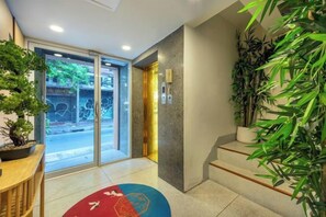 A hotel lobby with a reception desk, a staircase, and potted plants. - Shin Hotel Chinatown (Bangkok)