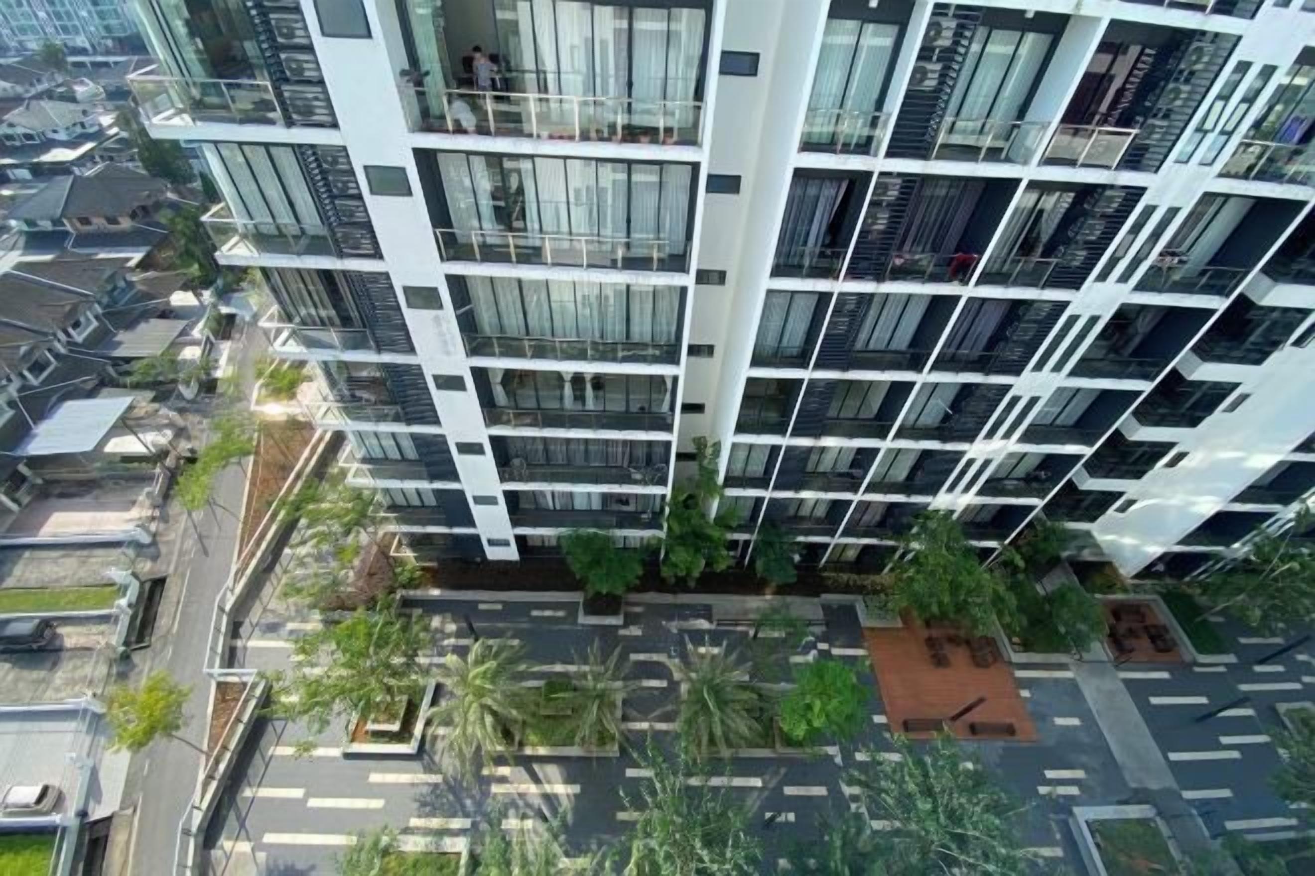 A high-rise building with multiple balconies, a rooftop garden, and a parking area.