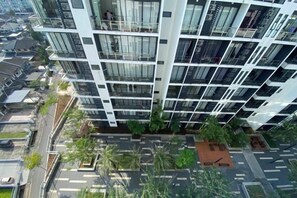 Un immeuble de grande hauteur doté de nombreux balcons, d’un jardin sur le toit et d’un espace de stationnement.