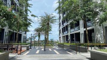 A modern urban street with multi-story buildings, palm trees, and a pedestrian walkway.