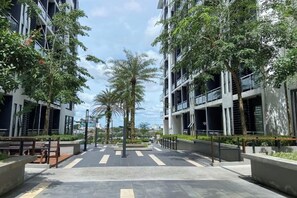 A modern urban street with multi-story buildings, palm trees, and a pedestrian walkway. - Gala Residences @ Galacity (Kuching)