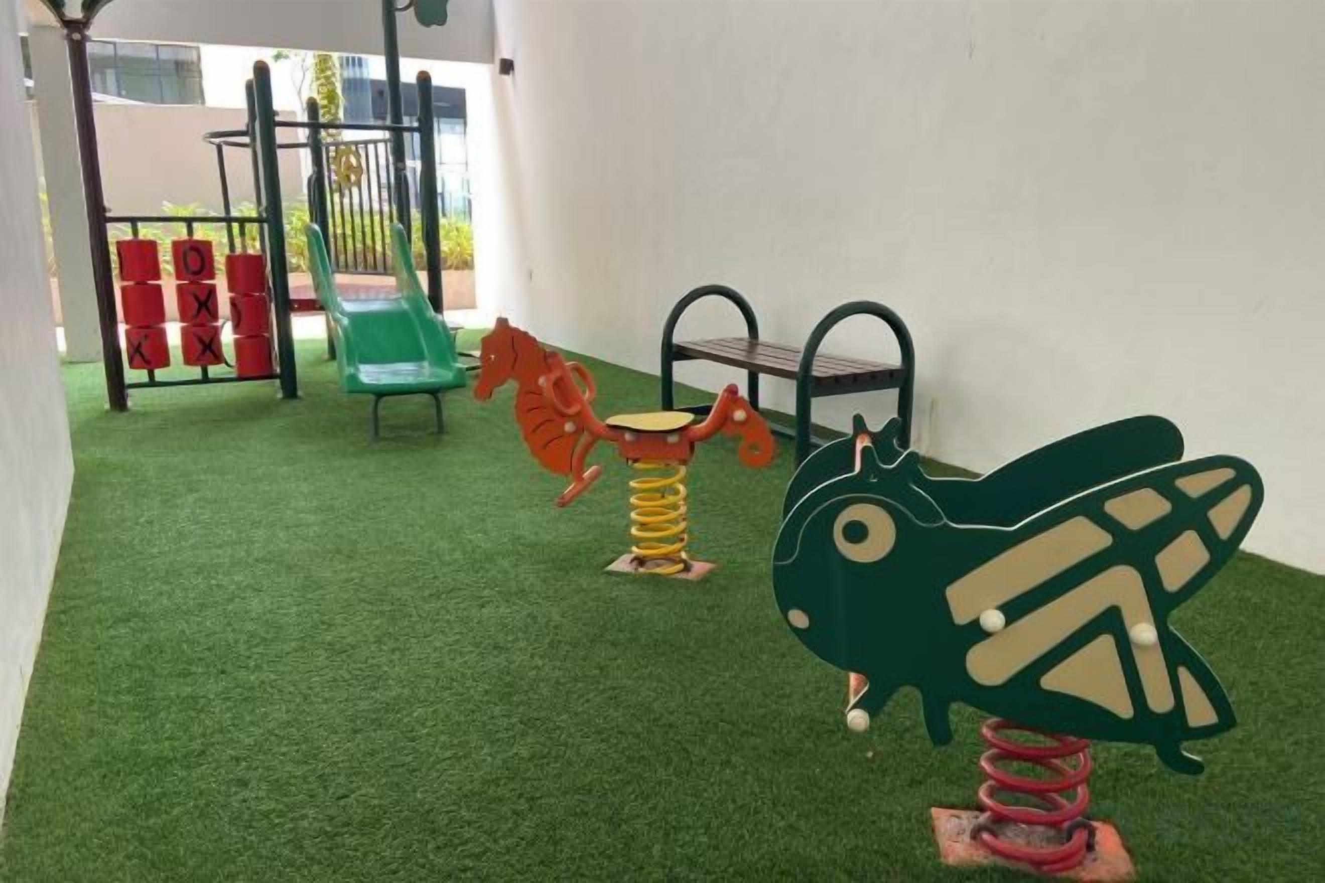 A children's play area with artificial turf, a green slide, and colorful play equipment.