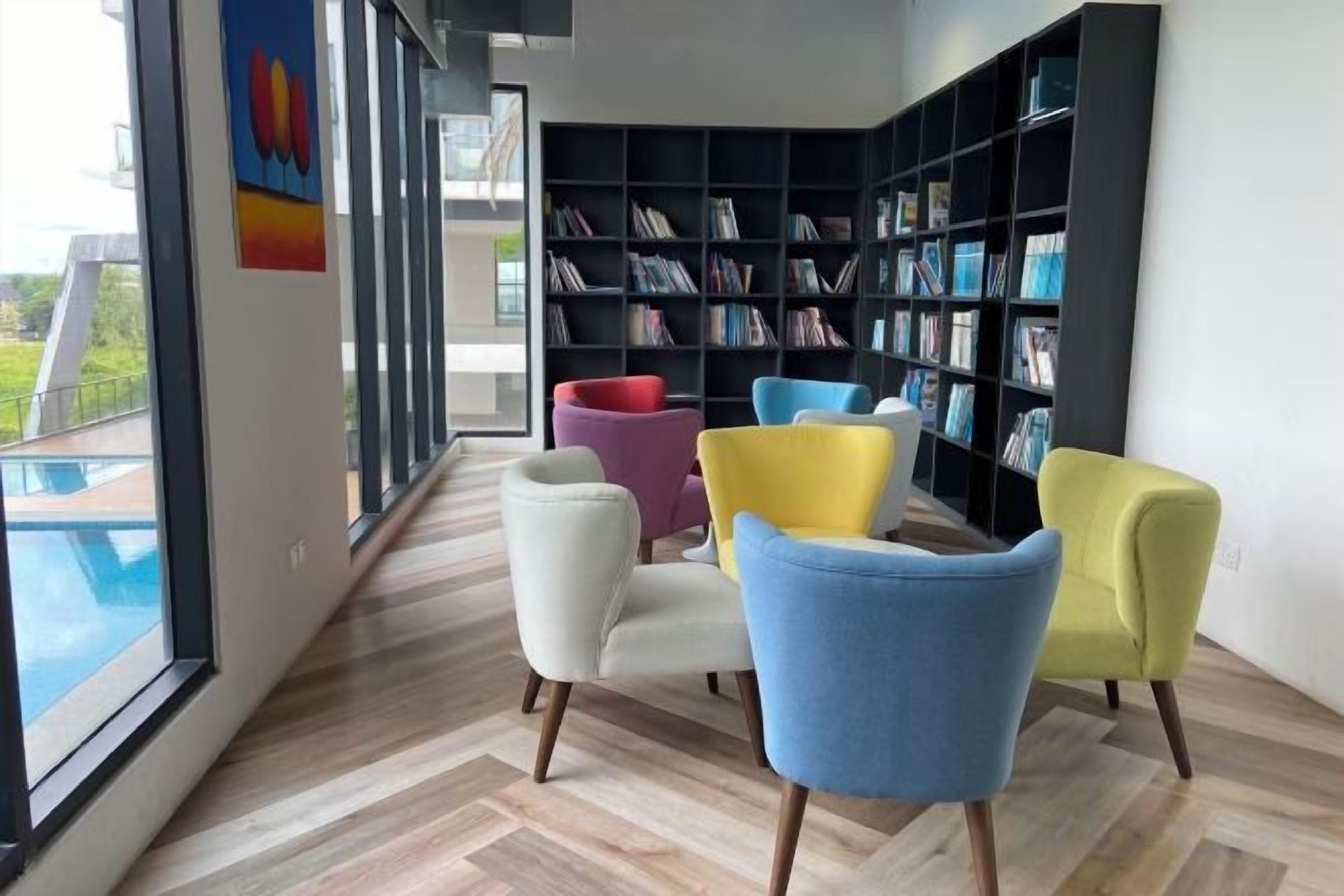 A modern interior with a large bookshelf, a pool view, and a herringbone floor pattern.